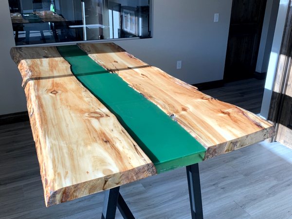 An epoxy river table with a green-tinted river vein.