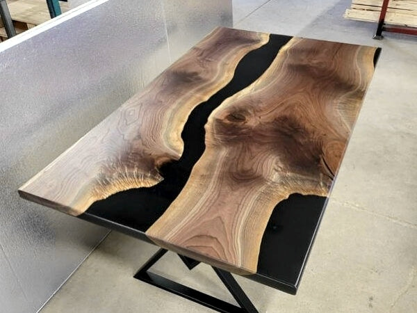 A wooden epoxy river table with black-tinted epoxy veins